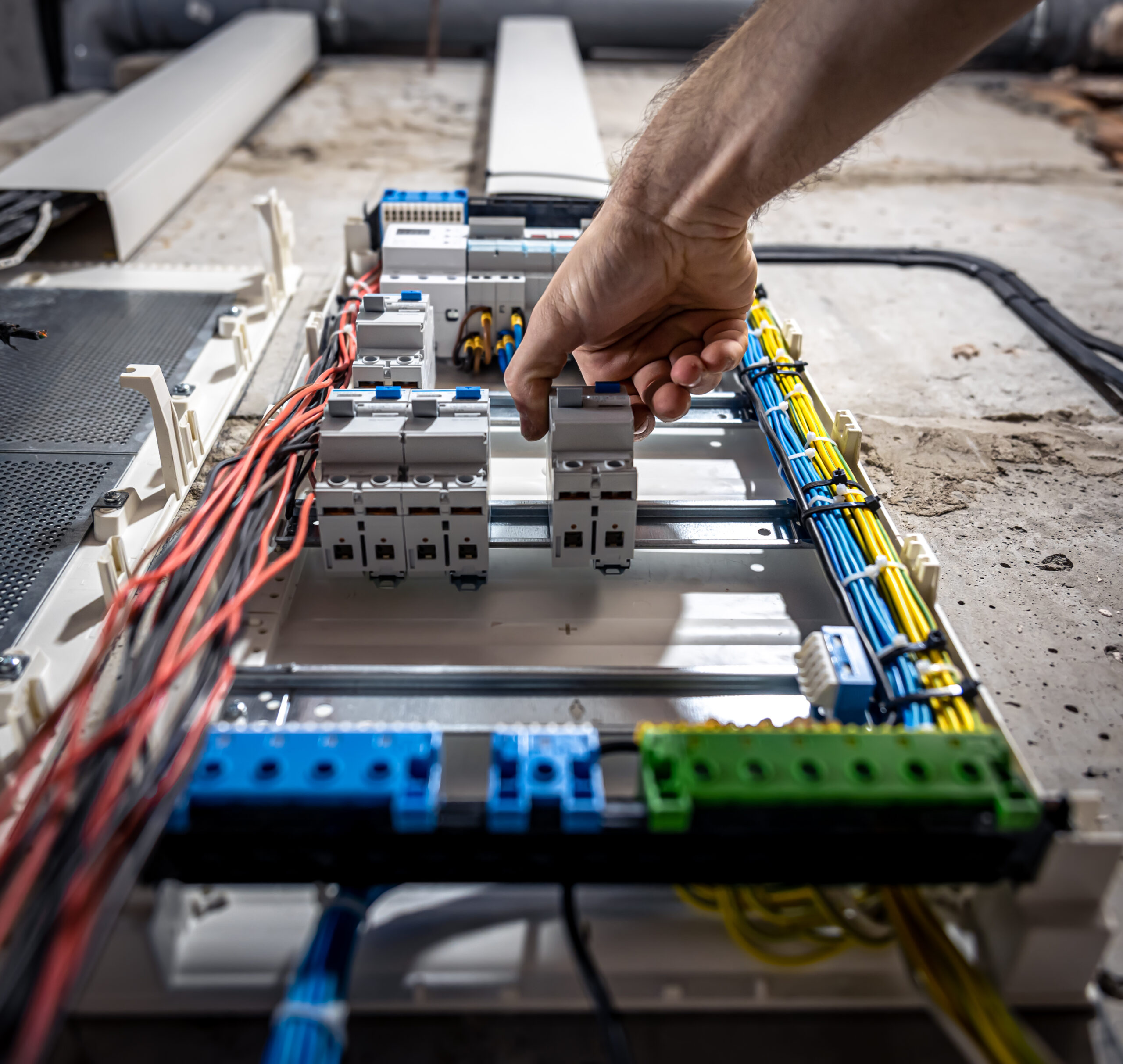 A male electrician works in a switchboard with an electrical connecting cable. Electrical Engineering